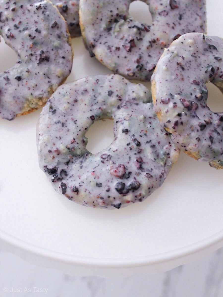 Blueberry donuts on a white plate topped with purple glaze.
