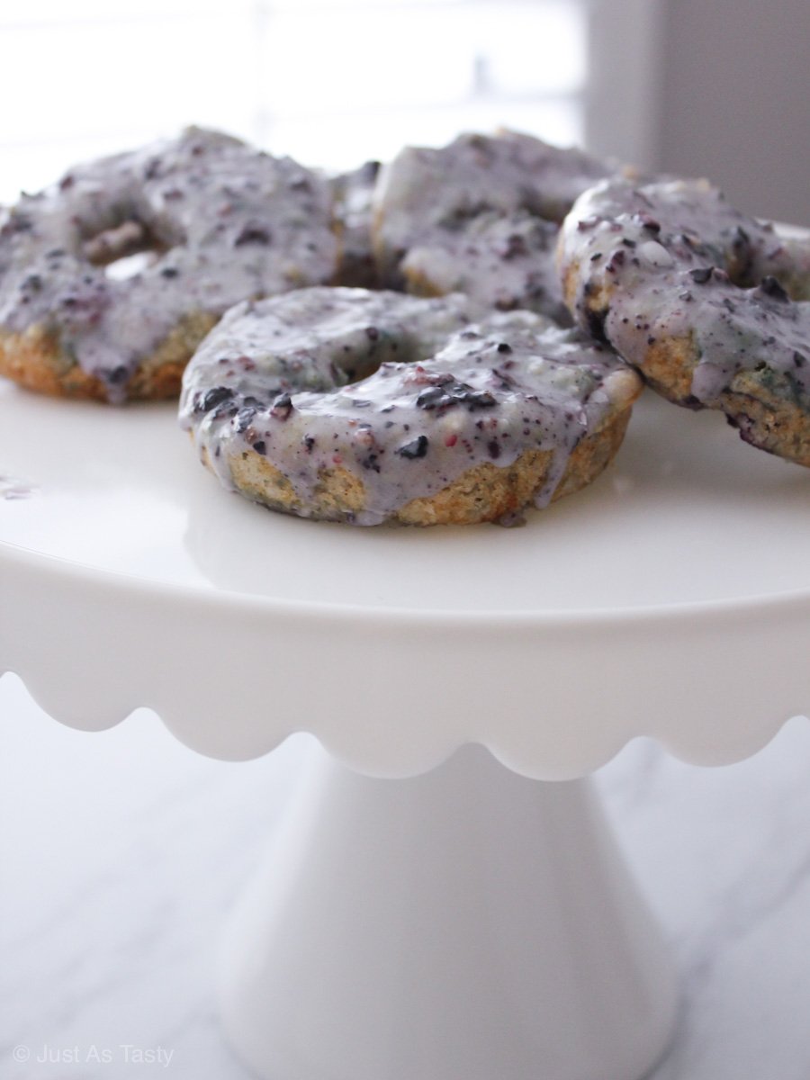 Purple glazed blueberry donuts on a white stand.