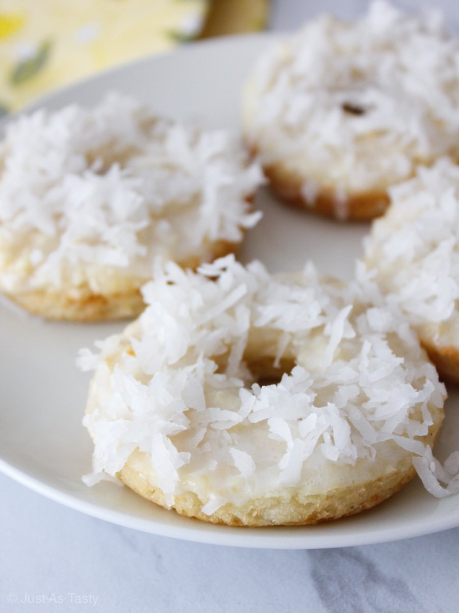 Donuts topped with coconut flakes on a white plate
