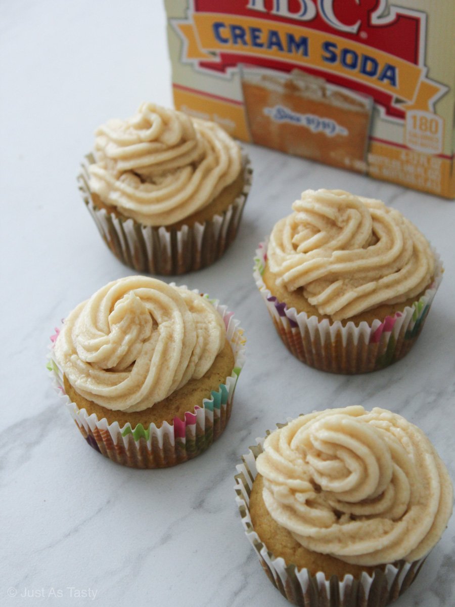 Cream soda cupcakes with swirl frosting on a white marble surface.