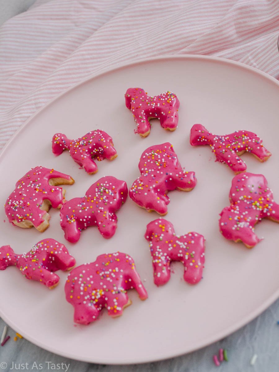 Pink circus animal cookies topped with sprinkles on a pink plate.