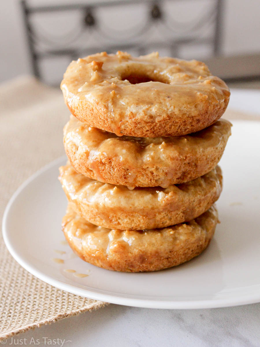 Stack of four maple glazed donuts on a white plate.