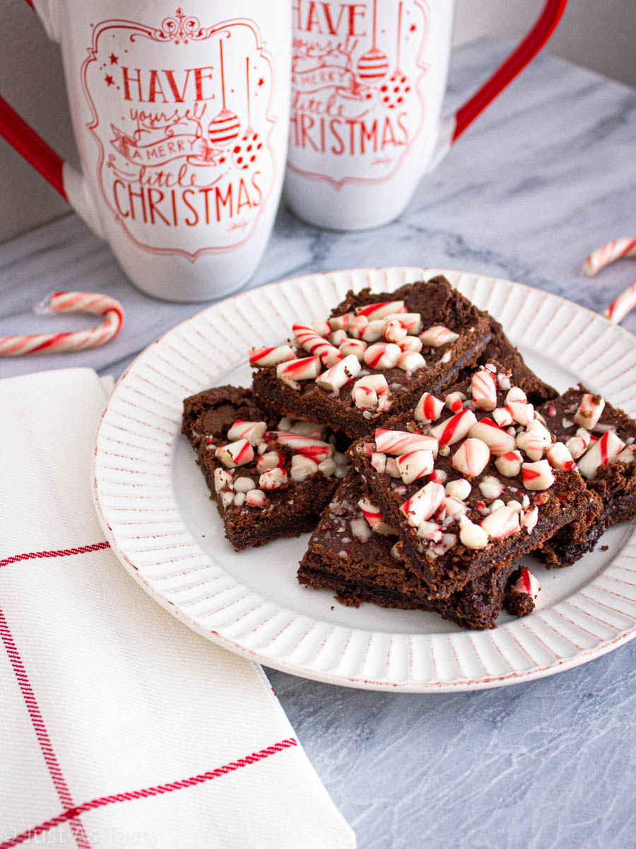 Peppermint brownies topped with candy canes on a white plate. 