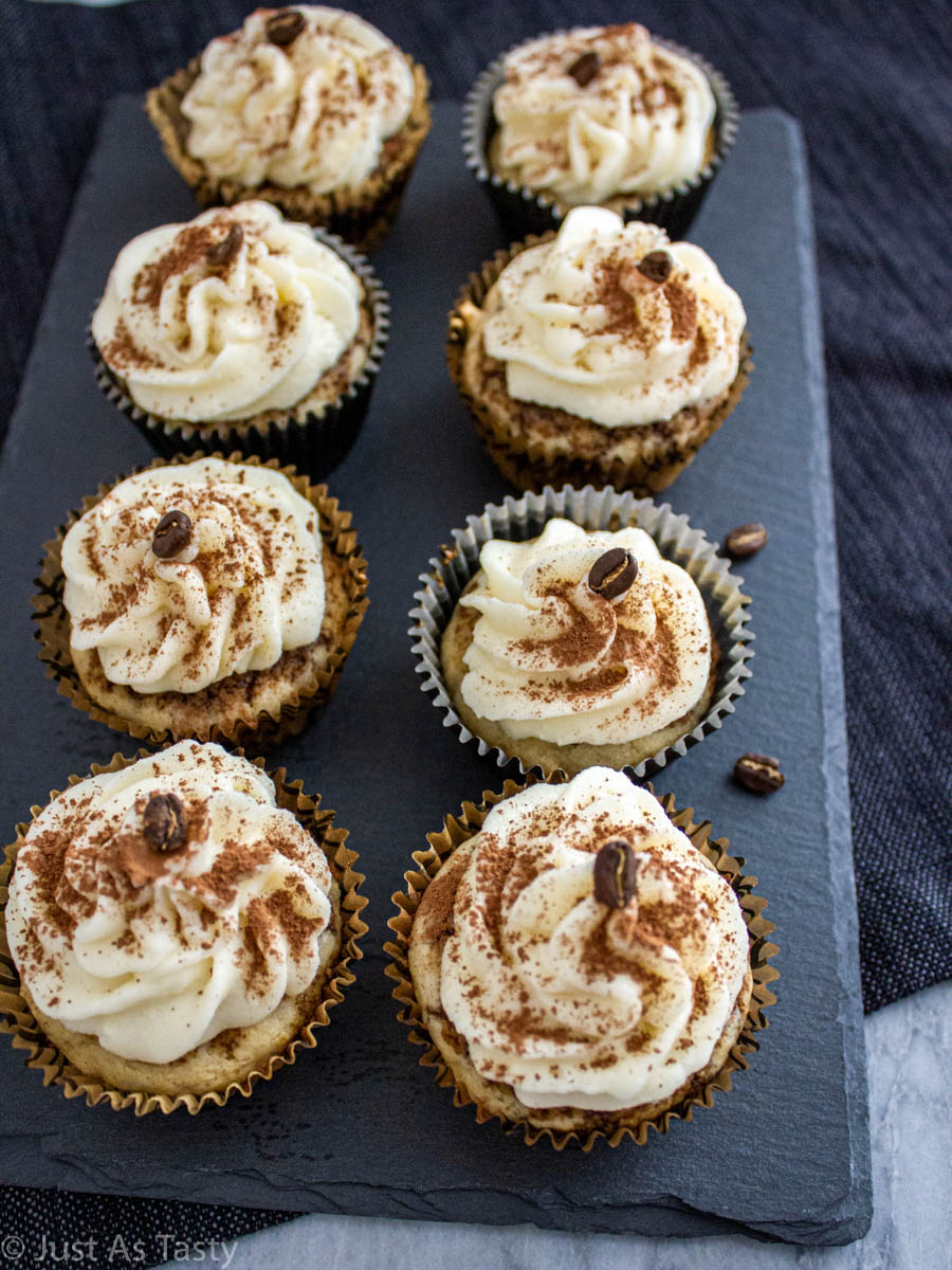 Frosted gluten free tiramisu cupcakes on a grey surface.