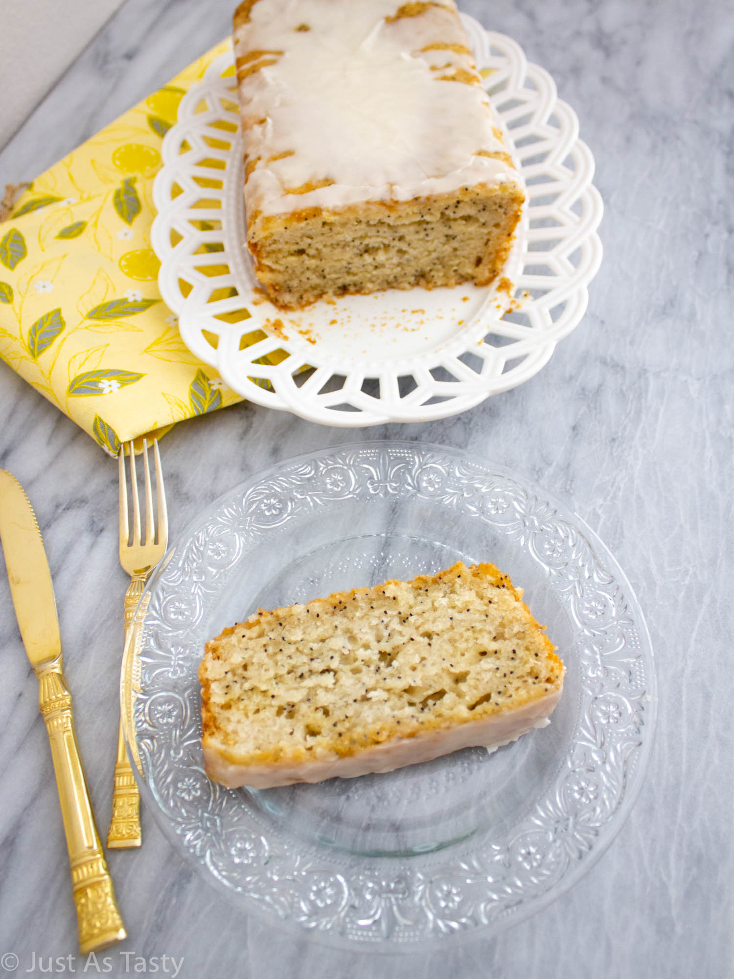 Slice of lemon poppy seed loaf on a glass plate.