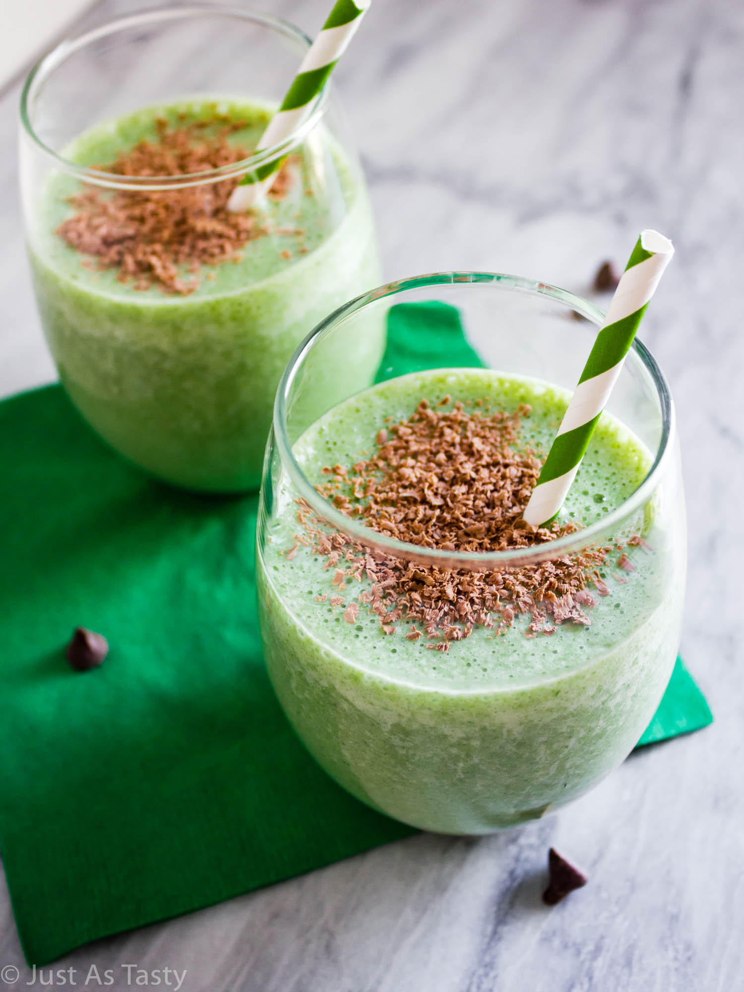Two healthy shamrock shakes in glasses with shaved chocolate on top.