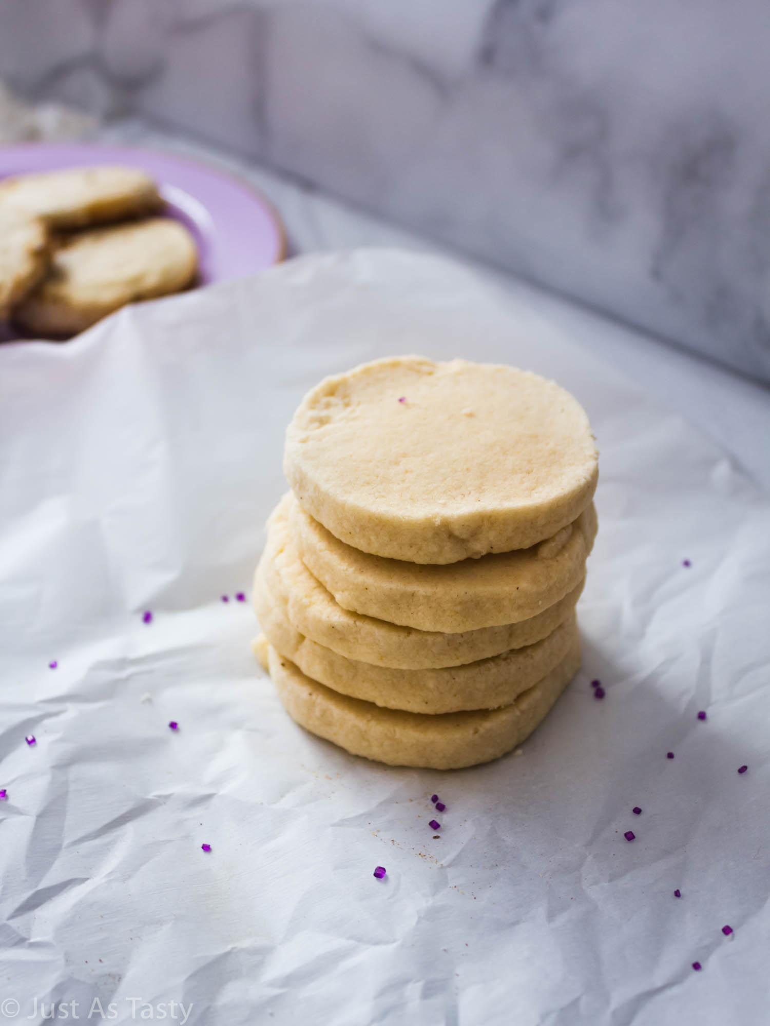 Stack of lavender shortbread cookies on parchment paper.