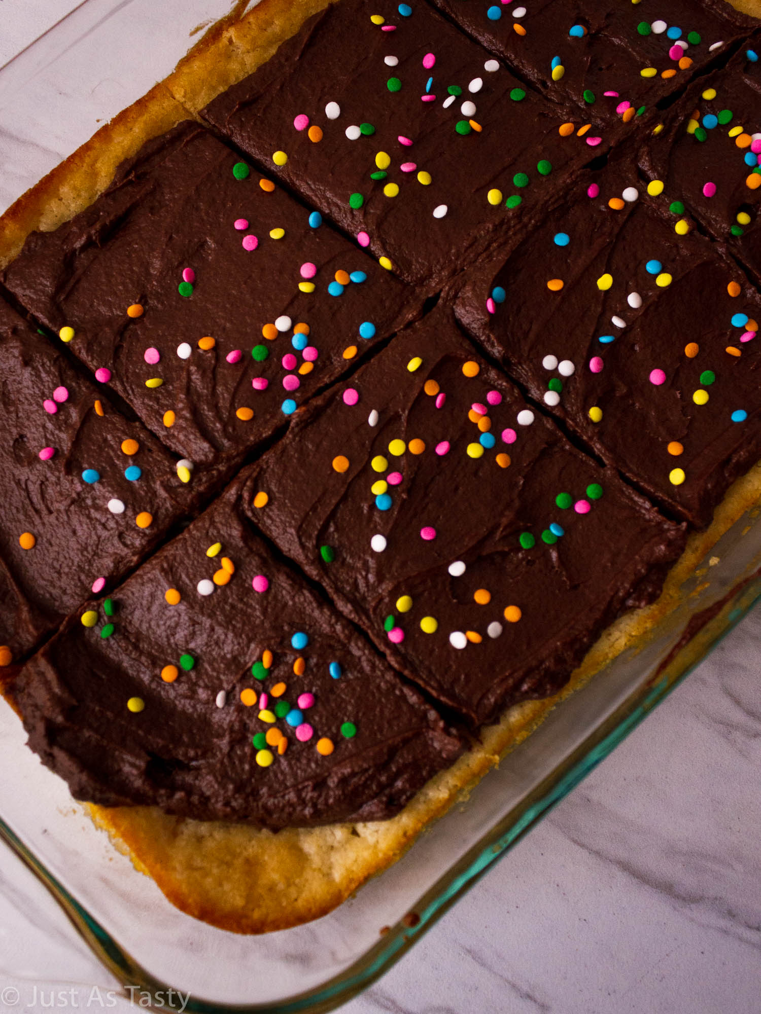Close-up of a sheet cake with chocolate frosting and sprinkles. 