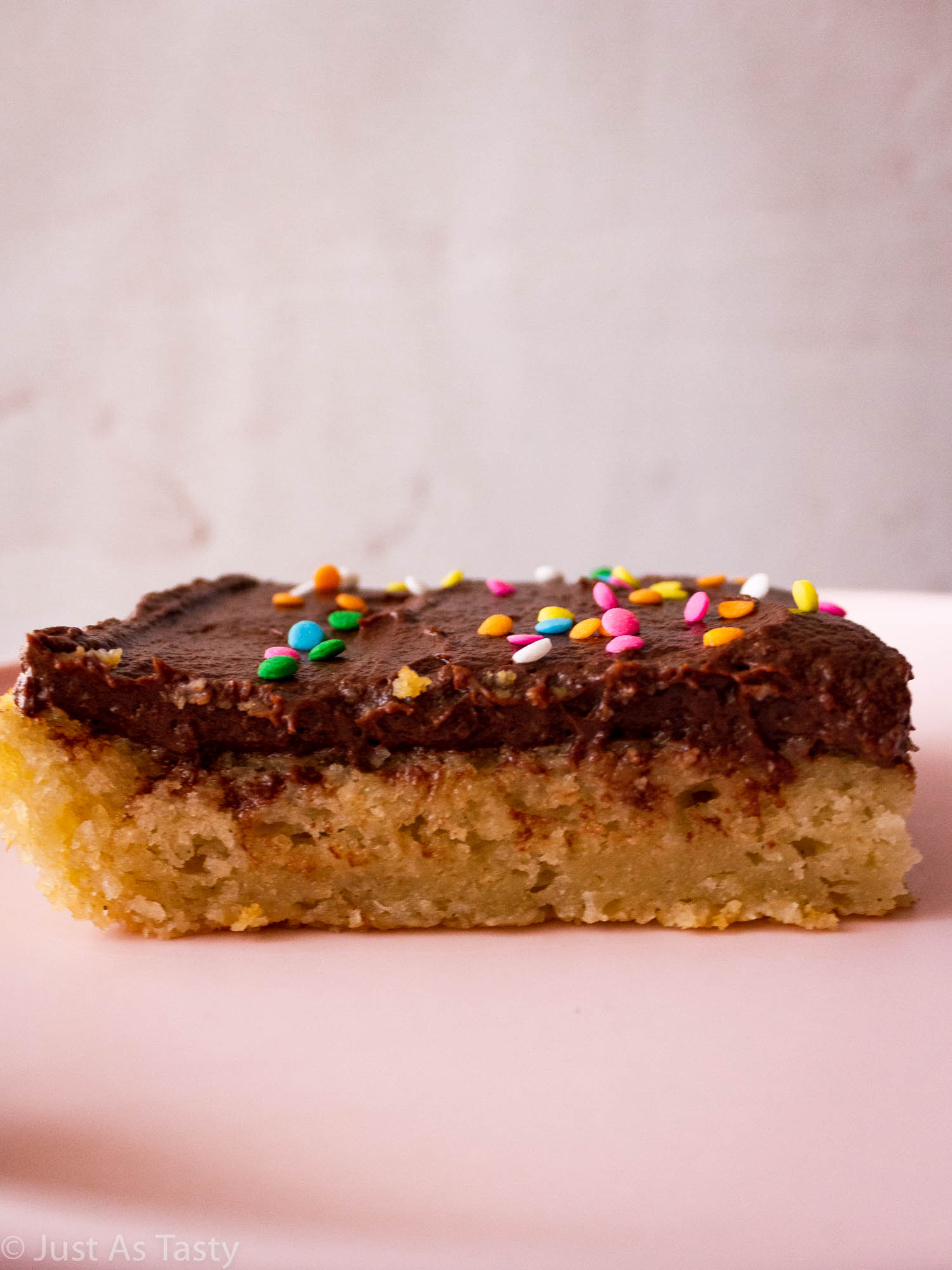 Close-up of a slice of yellow sheet cake with chocolate frosting. 