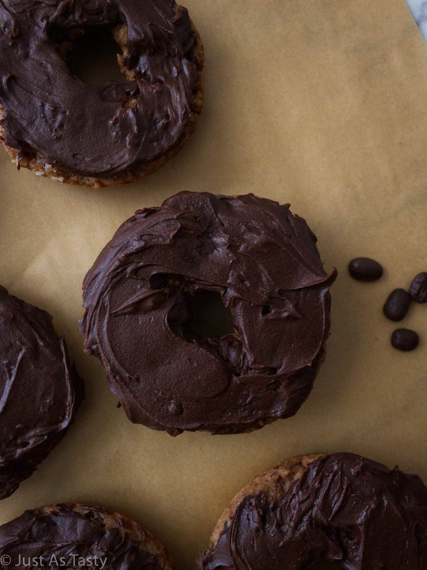 Close-up of a chocolate covered coffee donut on brown parchment paper.