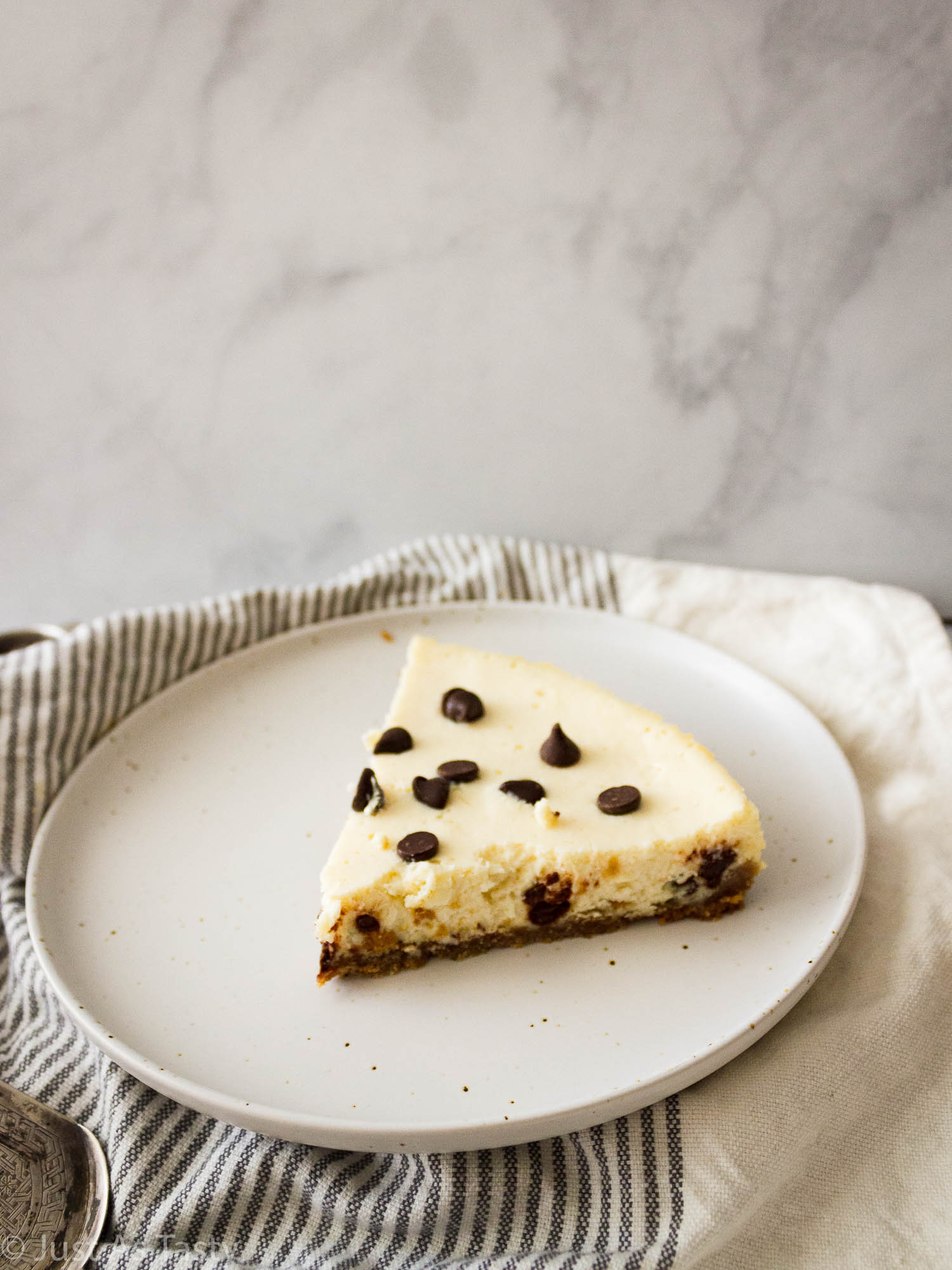 Slice of chocolate chip cheesecake on a white plate.
